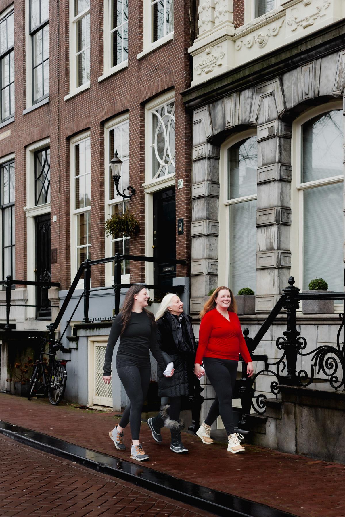 Three women walking together through an Amsterdam street during a family photo session.