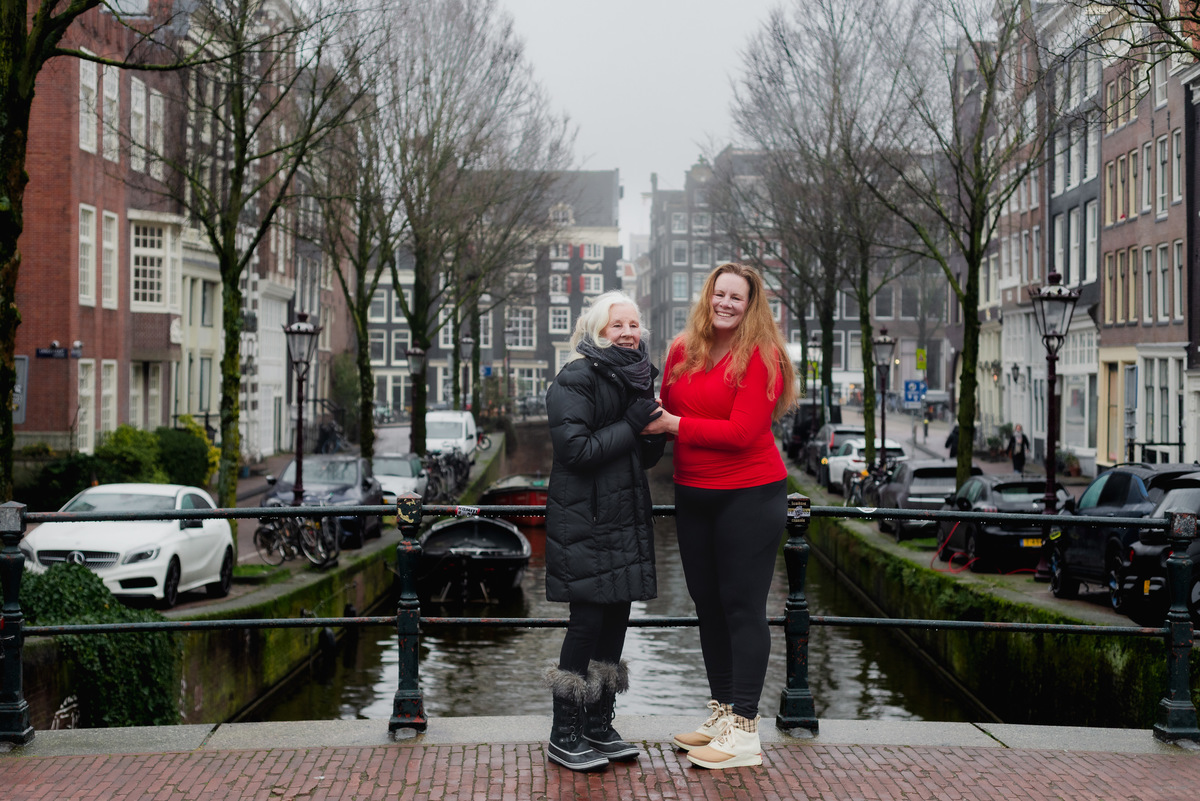 Woman in a red sweater standing beside an Amsterdam canal on a winter day.
