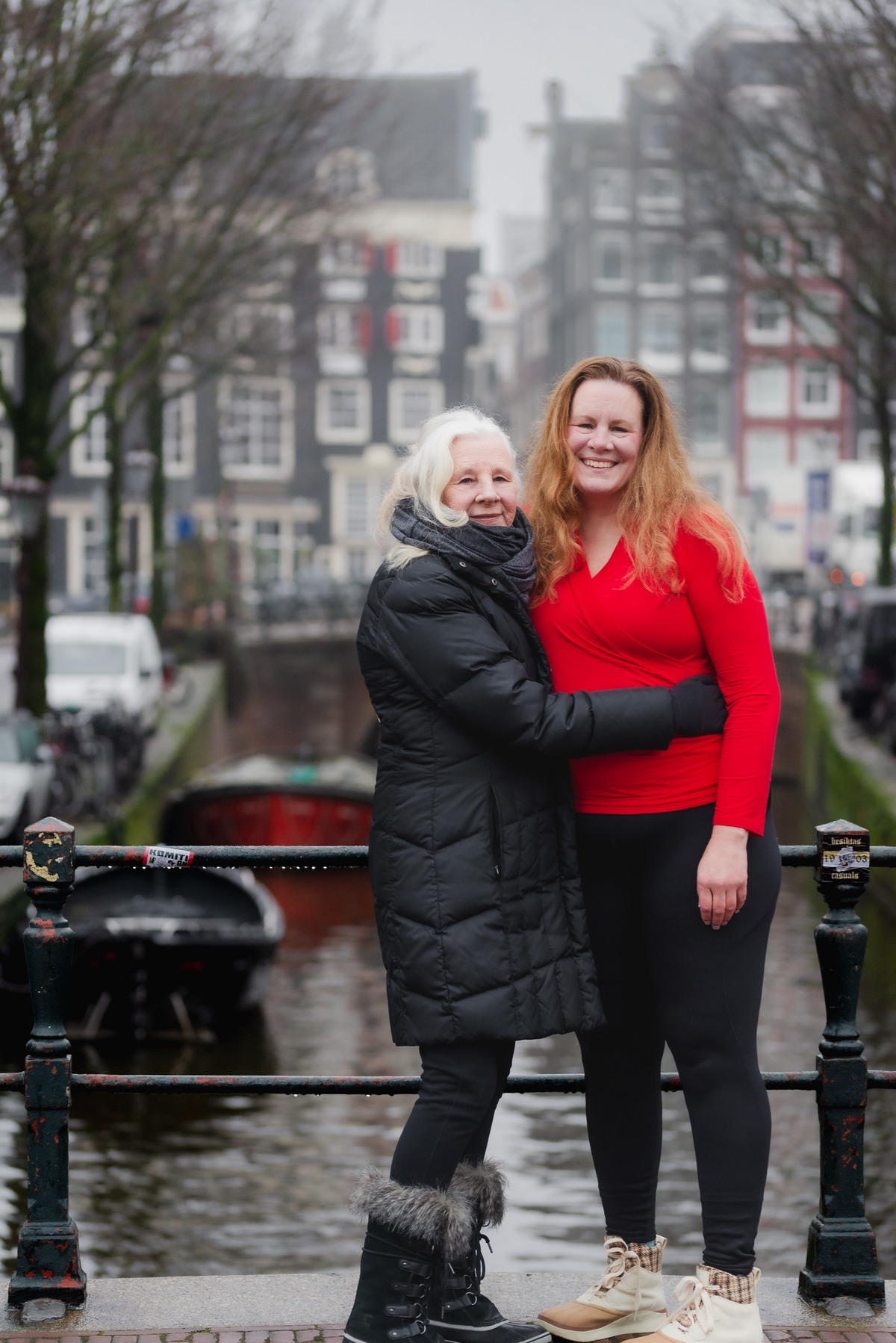 Two women embracing beside a canal during a family birthday photo session in Amsterdam.