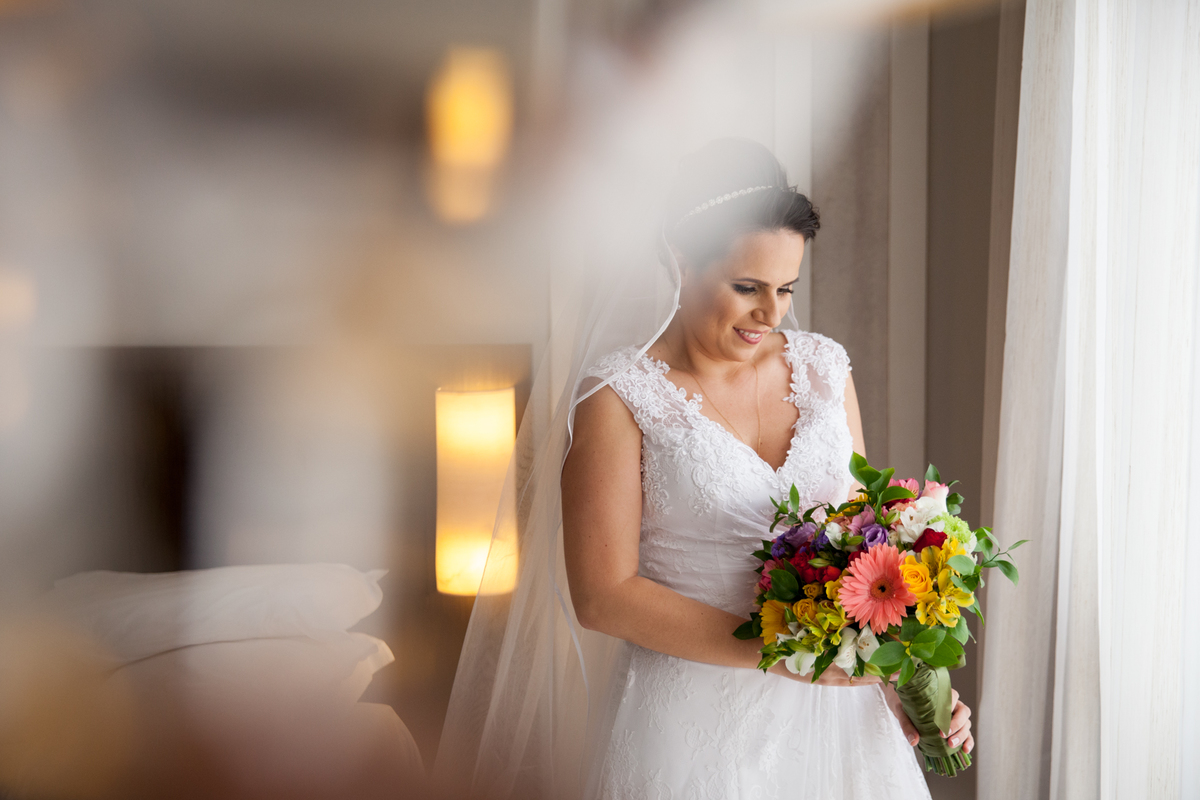 noiva olhando para o buque no dia do casamento, buque com flores coloridas 