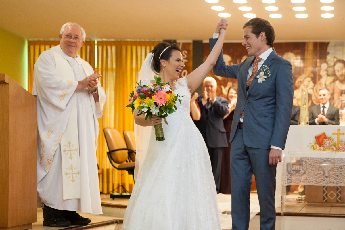 padre no lado direito aplaudindo a saida dos noivos no altar