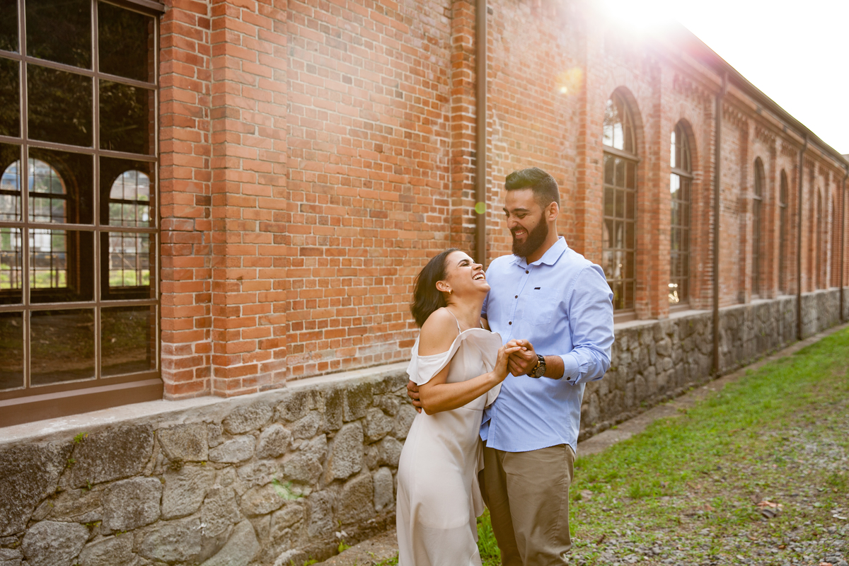 fotos de ensaio, pre wedding dos noivos em Paranapiacaba, noivo abracando a noiva, Paranapiacaba, São Paulo - Sp com fundo da parede de tijolinhos da antiga estacao de trem