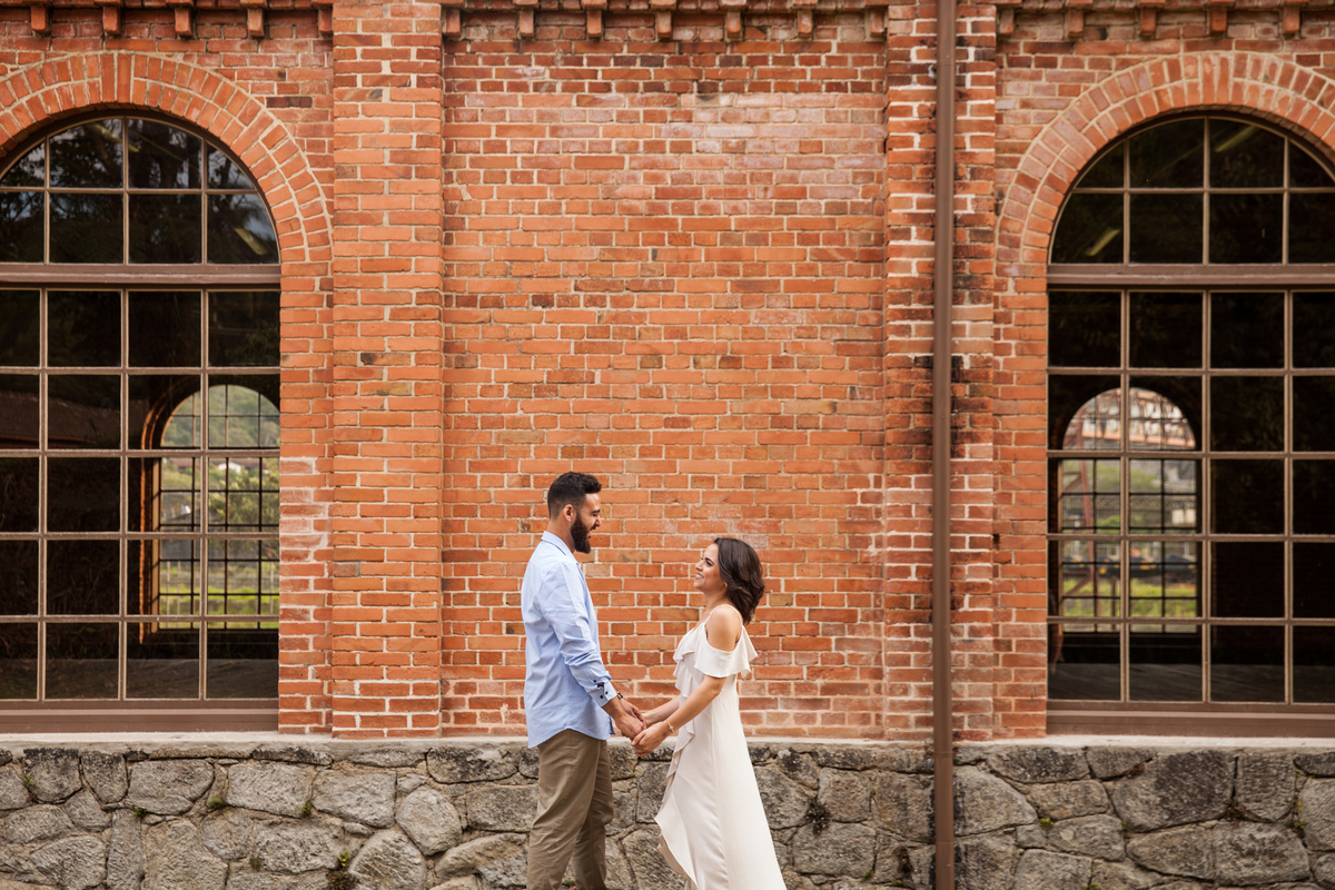 fotos de ensaio, pre wedding dos noivos em Paranapiacaba, noivo de frente a  noiva, Paranapiacaba, São Paulo - Sp com fundo da parede de tijolinhos da antiga estacao de trem, 