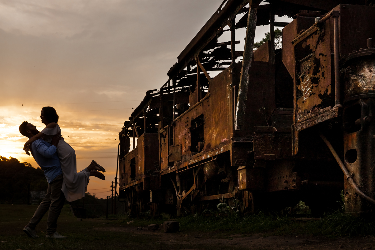 fotos de ensaio, pre wedding dos noivos em Paranapiacaba, noivo alevantando a noiva, Paranapiacaba, São Paulo - Sp com trem velho abandonado ao lado direito