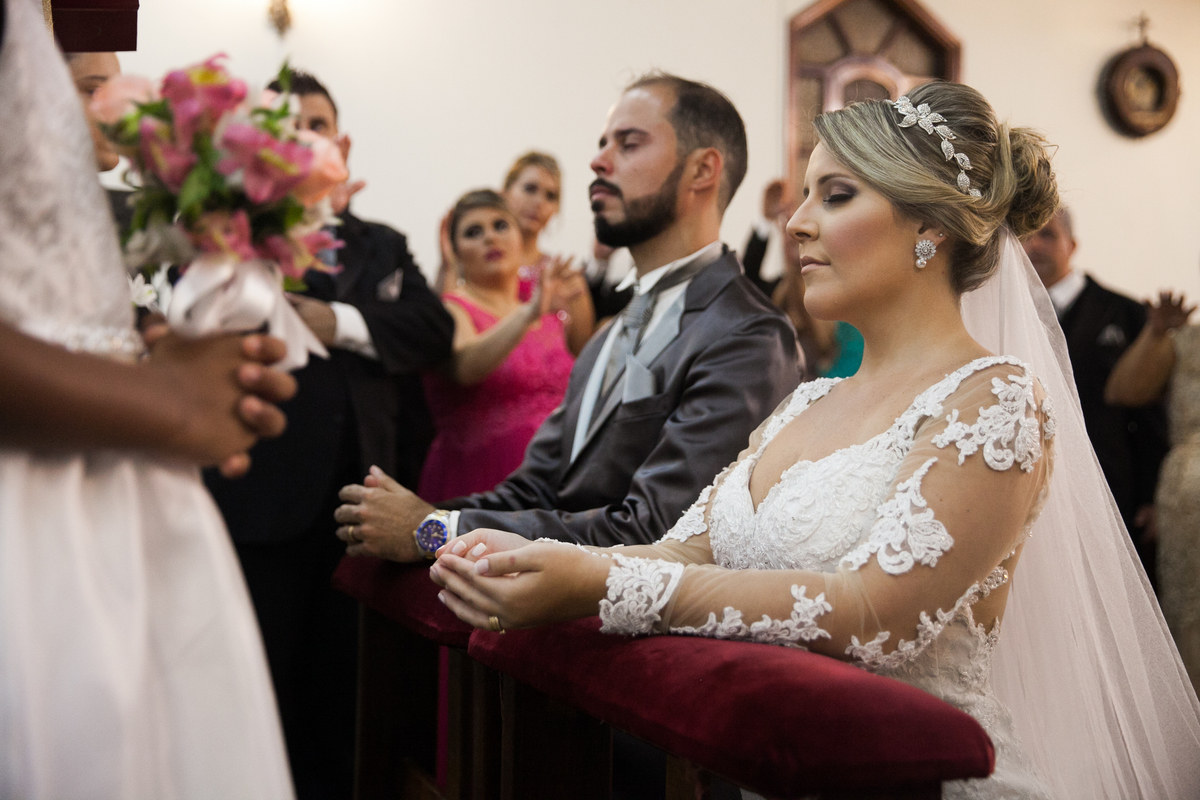 noivos ajoelhados recebendo a benção de casamento do padre