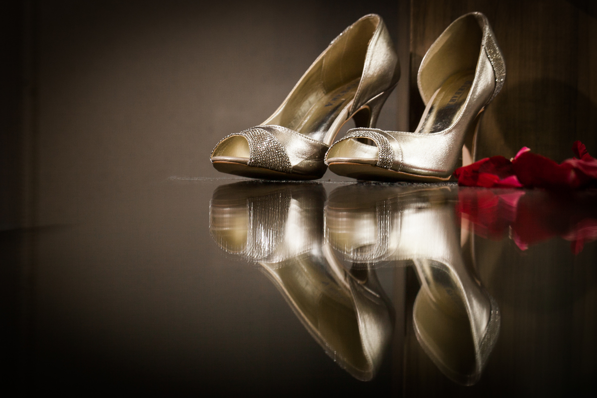 sapato da noiva com petalas rosas refletindo na mesa