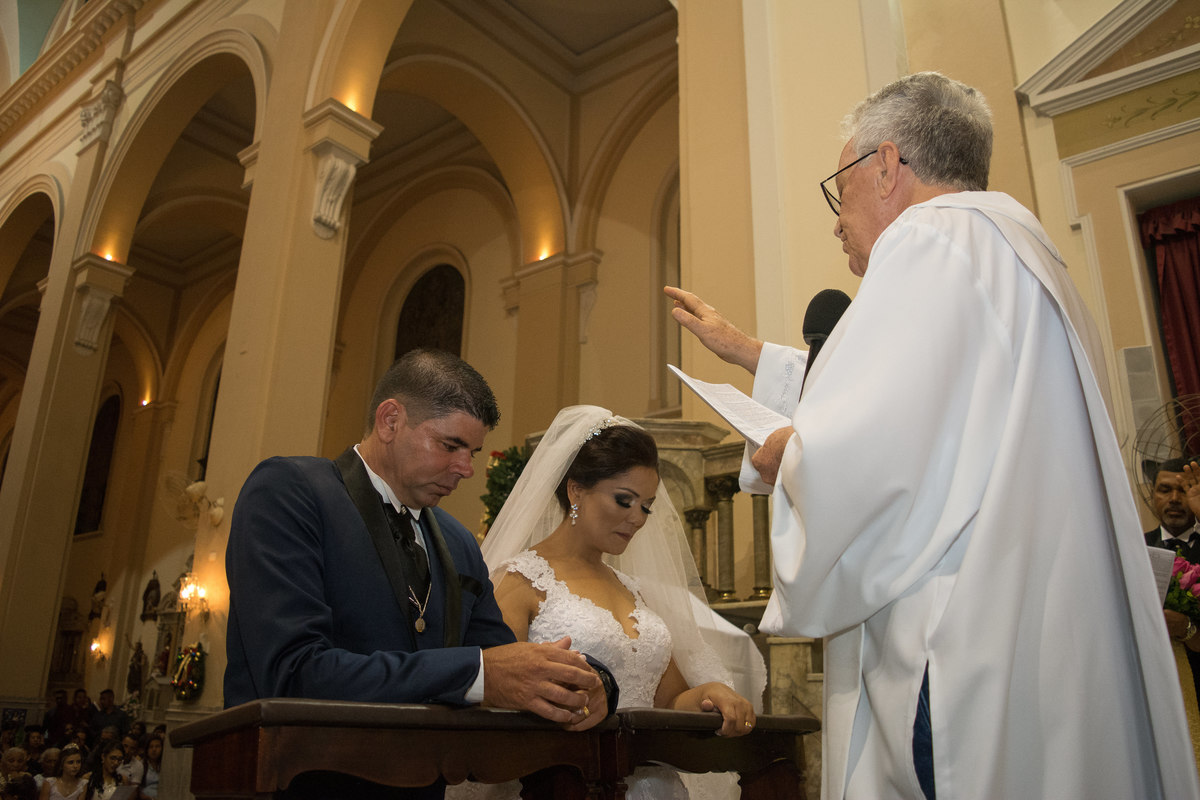 noivos sendo abencoados no dia do casamento, ajoelhados na igreja coração de maria em santos