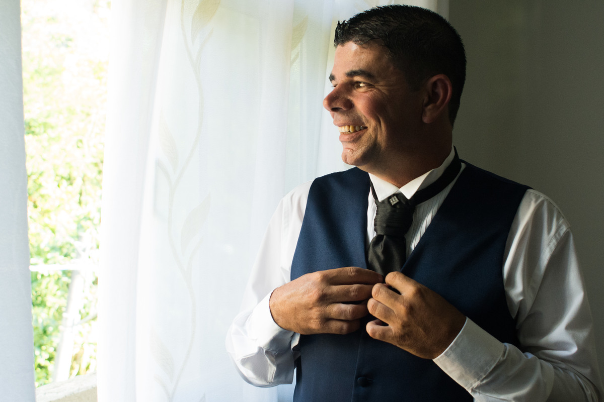 noivo olhando para fora, arrumando a gravata, casamento em santos na casa da crianca