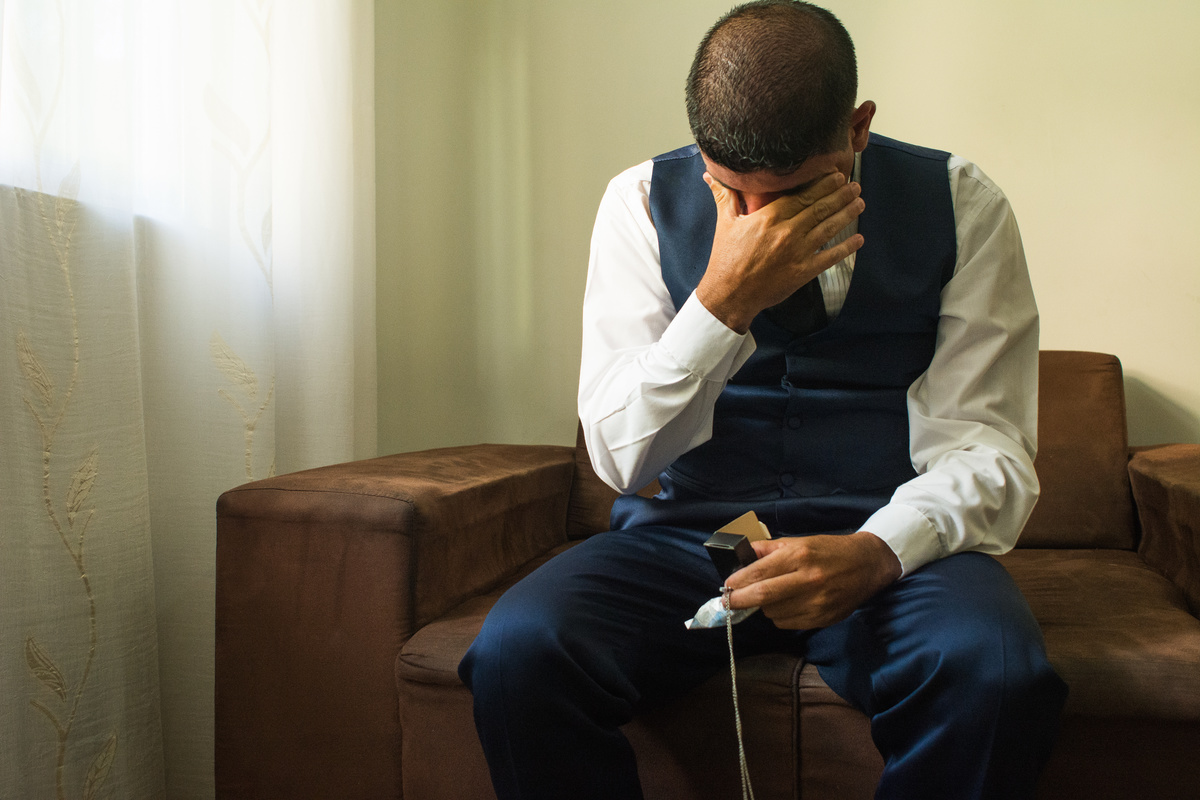 noivo emocionado com presente da noiva, corrente com imagem do pai falecido