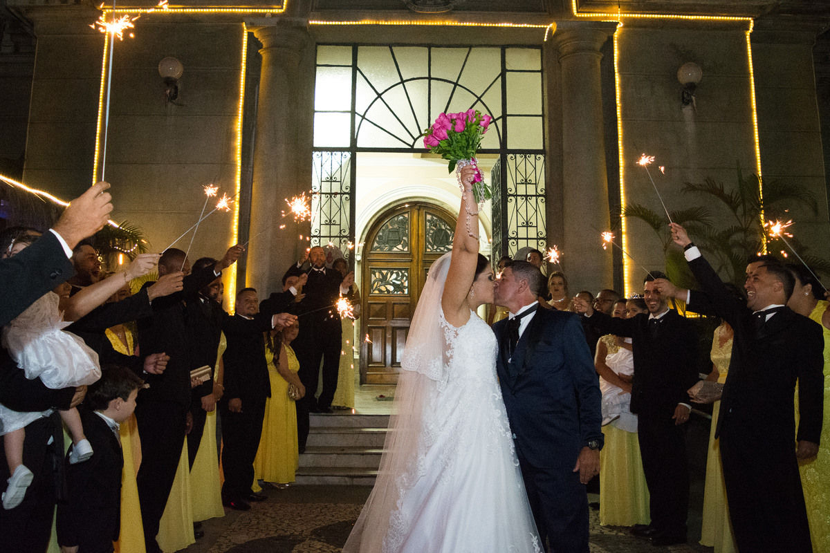 noiva com braco esticado comemorando em frente a igreja no final da cerimonia