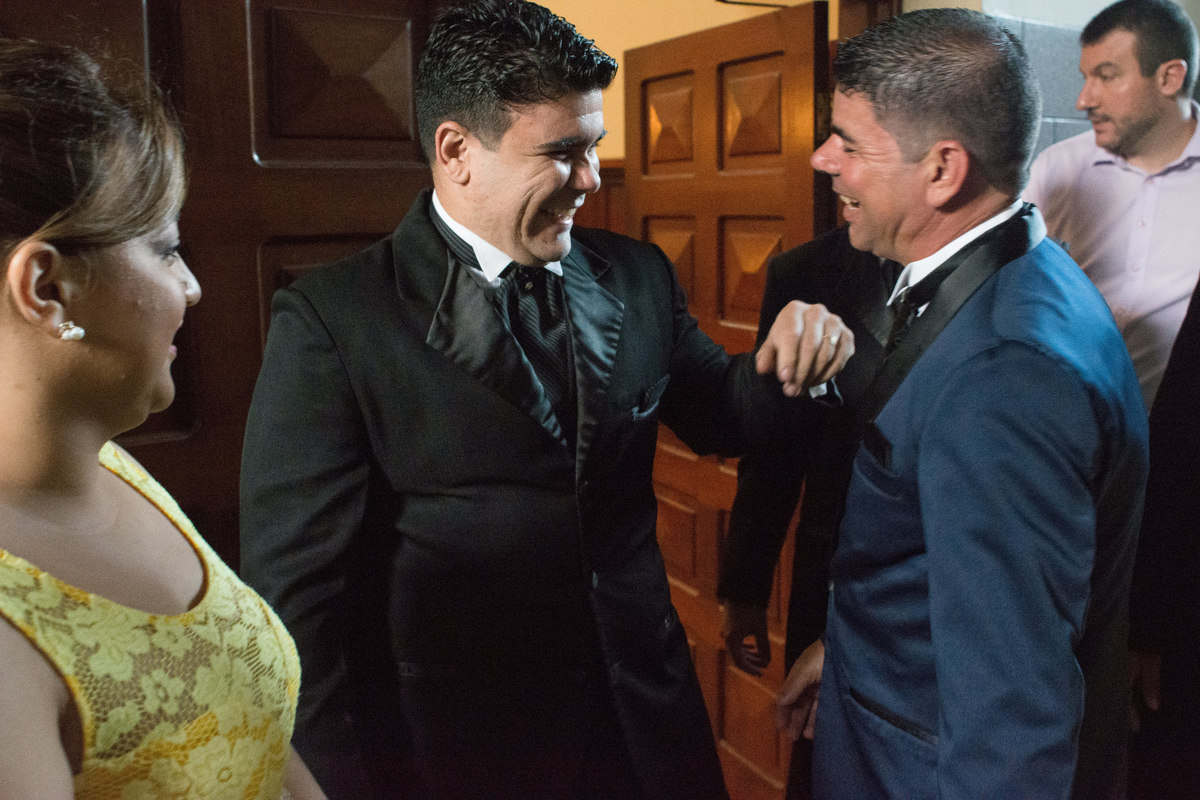 noivo recepcionando os convidados na porta da igreja, sorrindo e ansioso