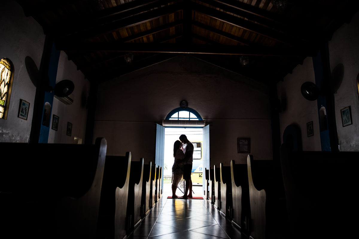 fotos de ensaio, pre wedding dos noivos em maresias, noivo abracando a noiva, Maresias, São Paulo - Sp dentro da capela so a silhueta