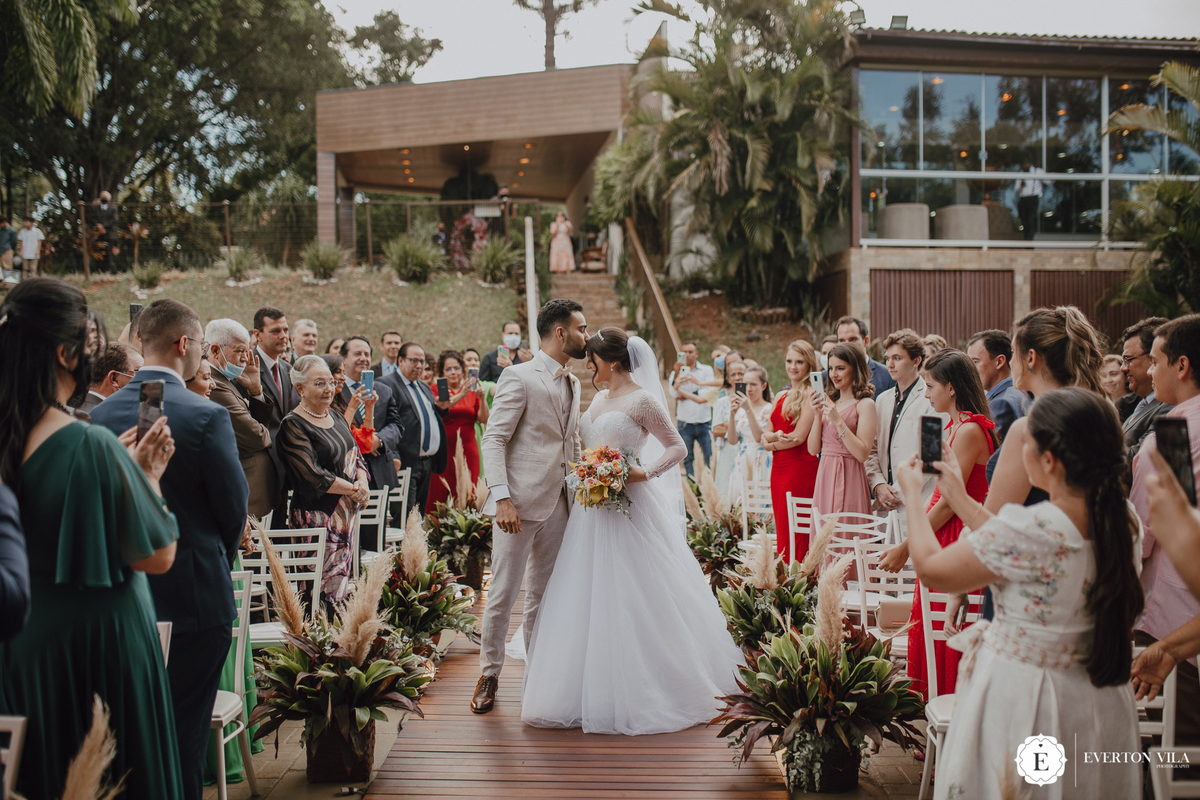 Noivo beijando a testa da noiva em cerimonia ao ar livre