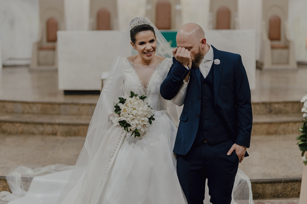 Noivo beijando a mão da noiva na saída do casamento na igreja