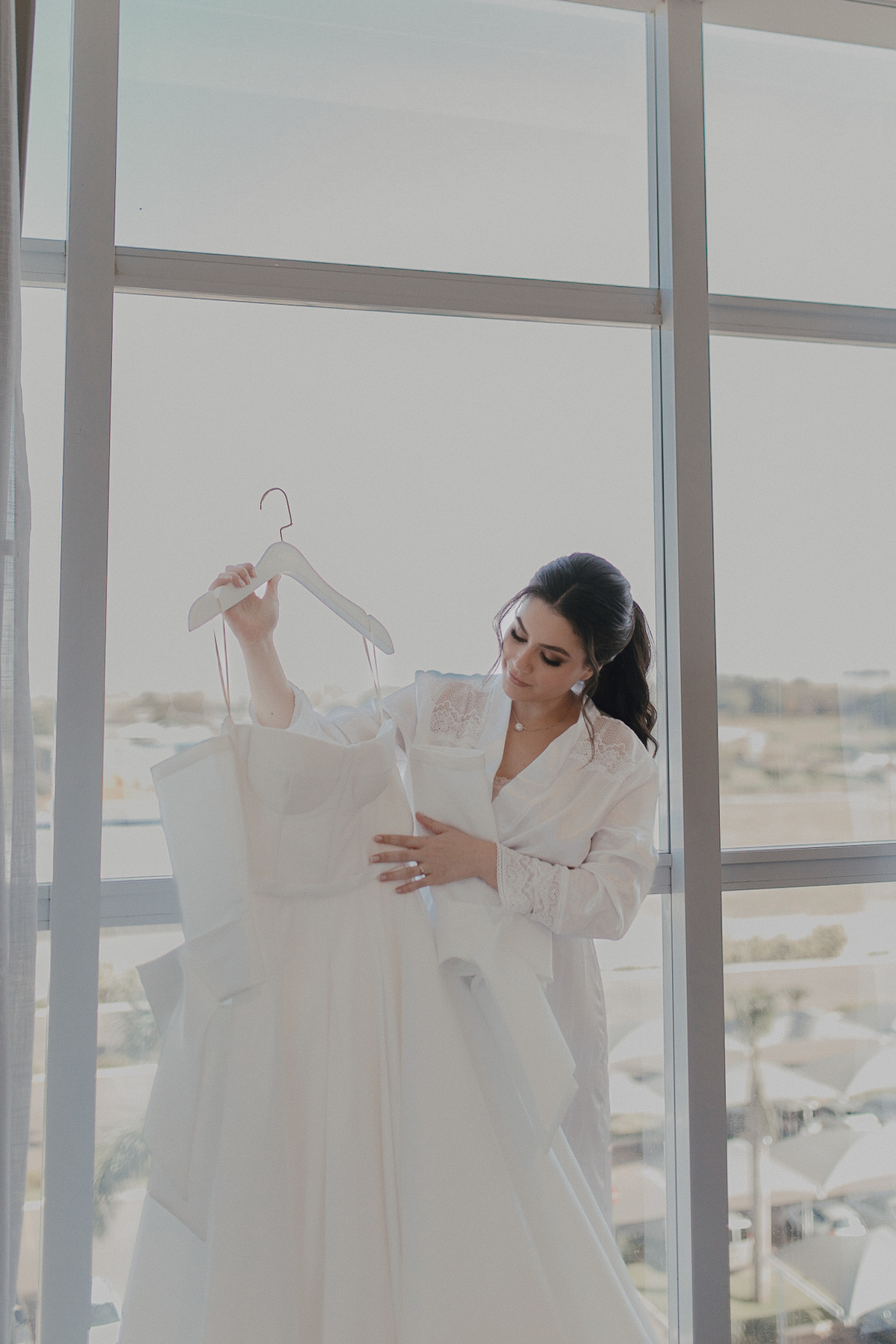 Noiva segurando seu vestido no making off em hotel com luz natural
