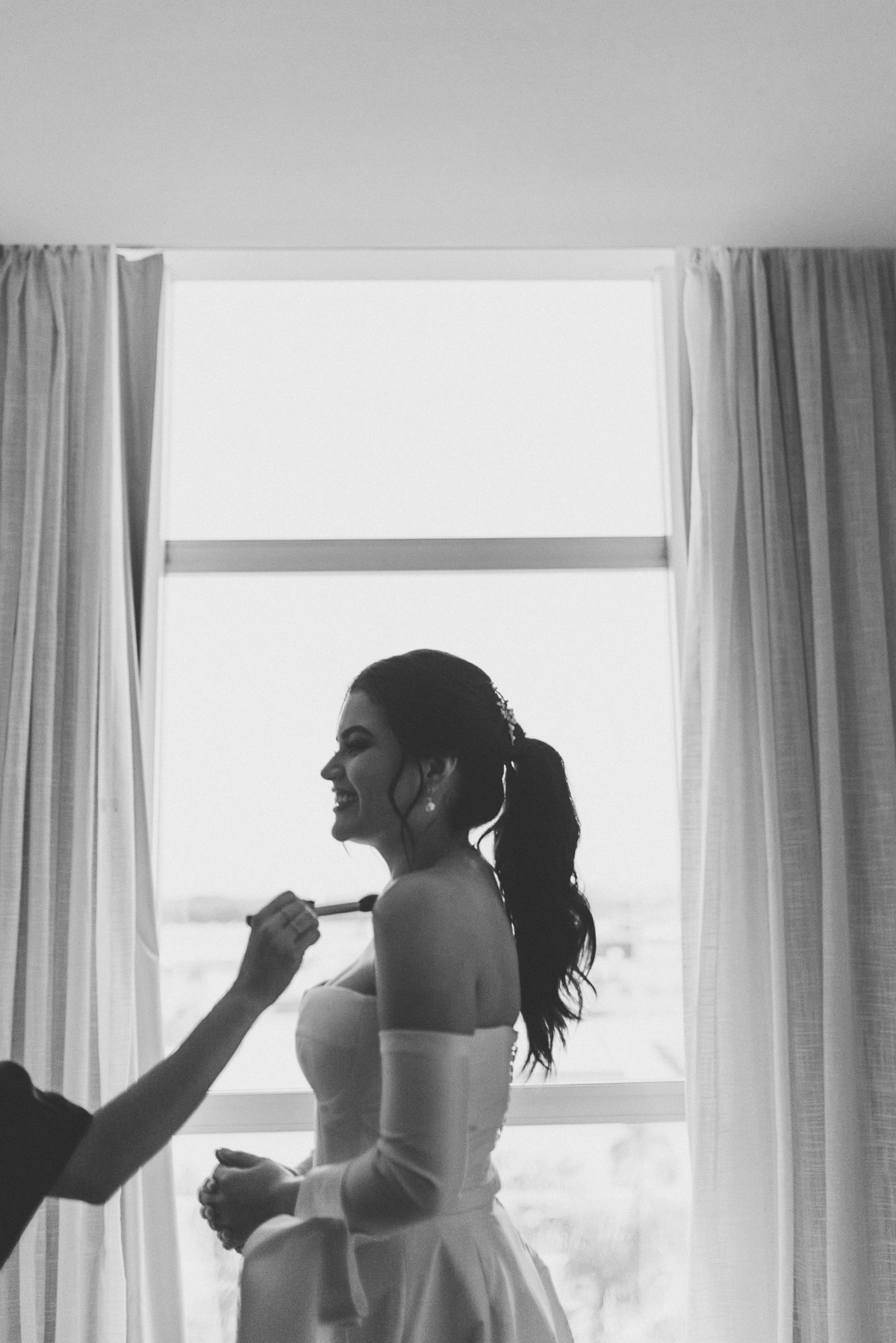 Noiva retocando a maquiagem em making off no hotel com luz natural