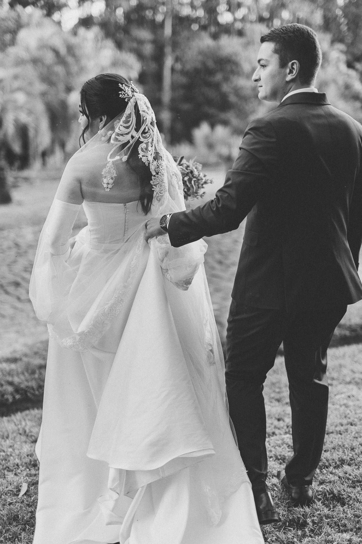 Noivo ajudando a noiva carregar vestido ao caminhar