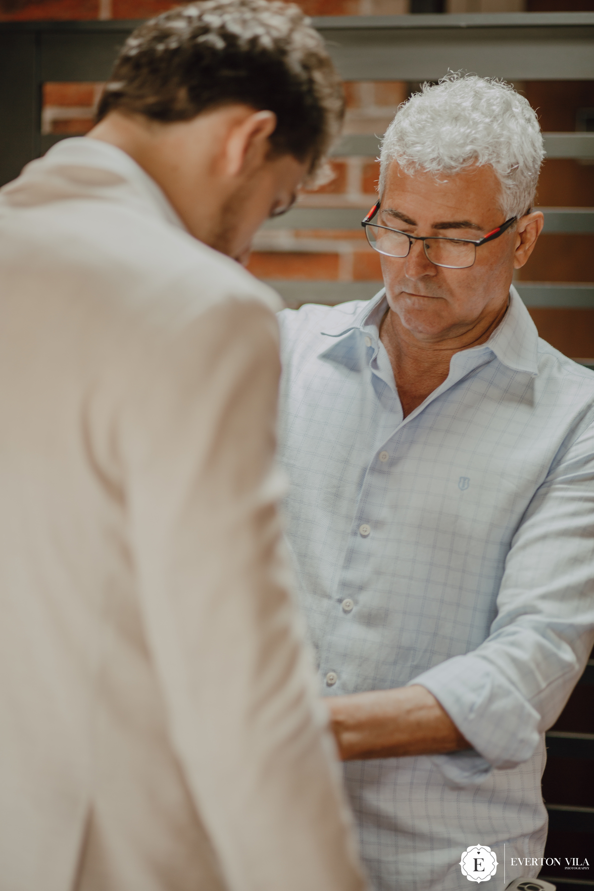 Pai do noivo ajudando seu filho se arrumar 
