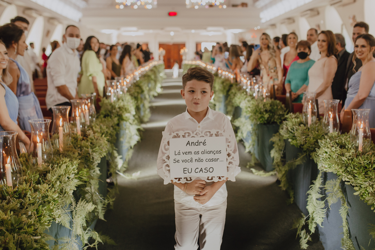 Pajem com plaquinha anunciando a entrada das alianças 