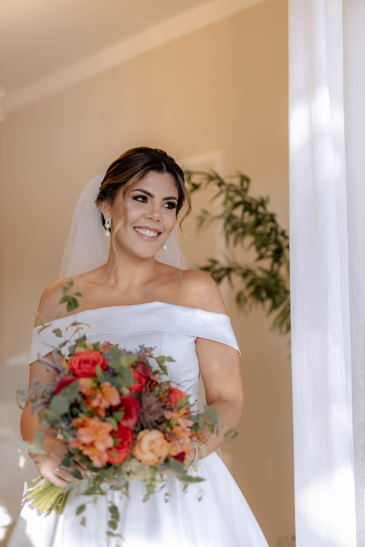 Noiva linda com coque descontraído e buquê com flores laranja