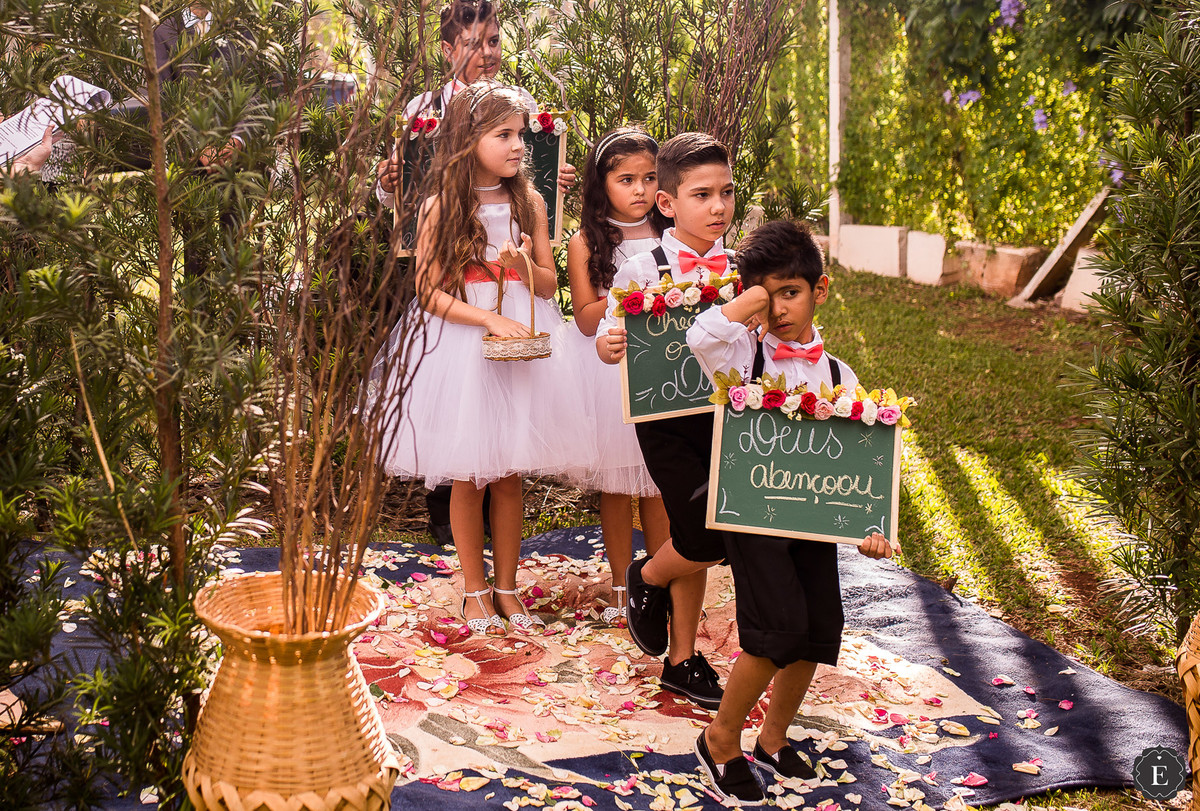 entrada de crianças com plaquinhas e cesta de flores para o casamento no campo