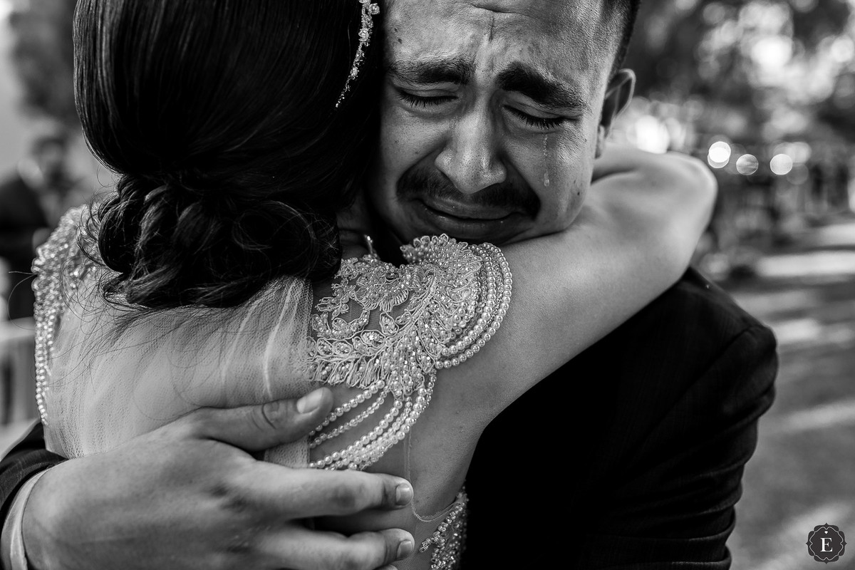 padrinho chorando ao abraçar noiva no casamento