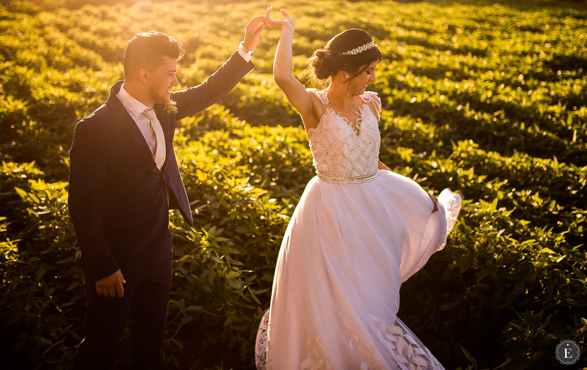 noivo girando a noiva com seu lindo vestido de noiva em fotos no campo