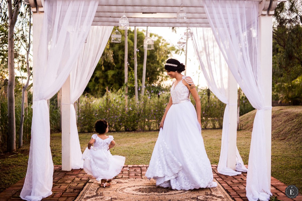 noiva feliz com daminha de honra em perolado brando de madeira decorado com tecido branco