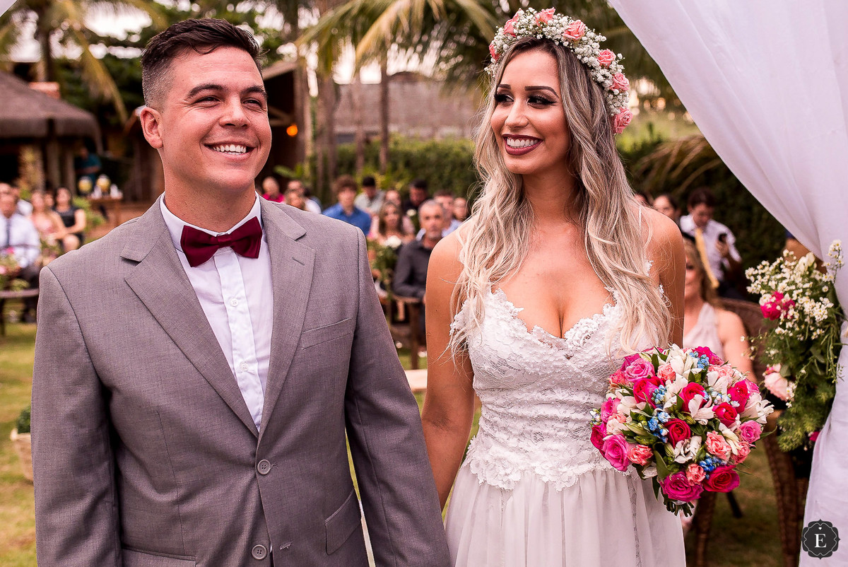 noivo com terno cinza e gravata bordo e noiva com vestido de renda e coroa de flores para casamento no campo