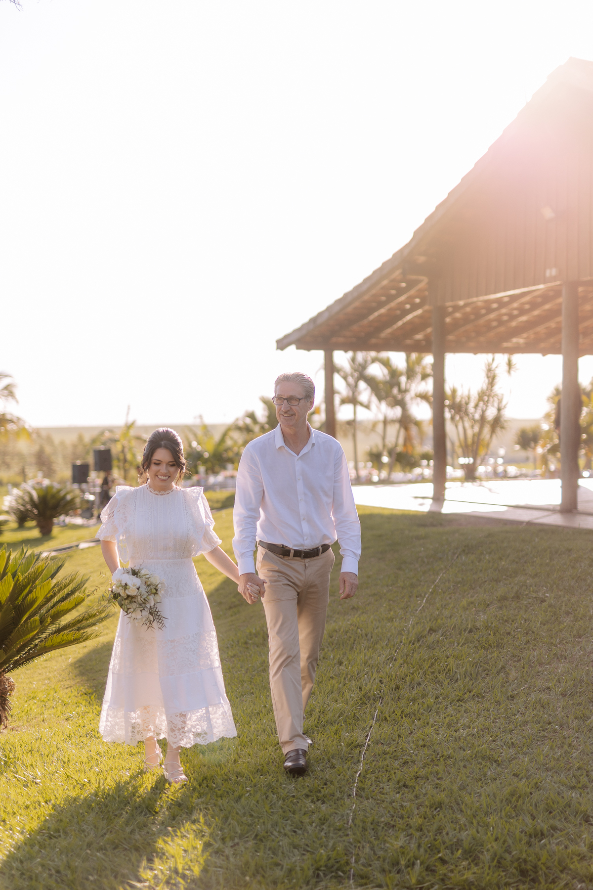 Noiva com seu pai caminhando em direção a cerimônia de casamento