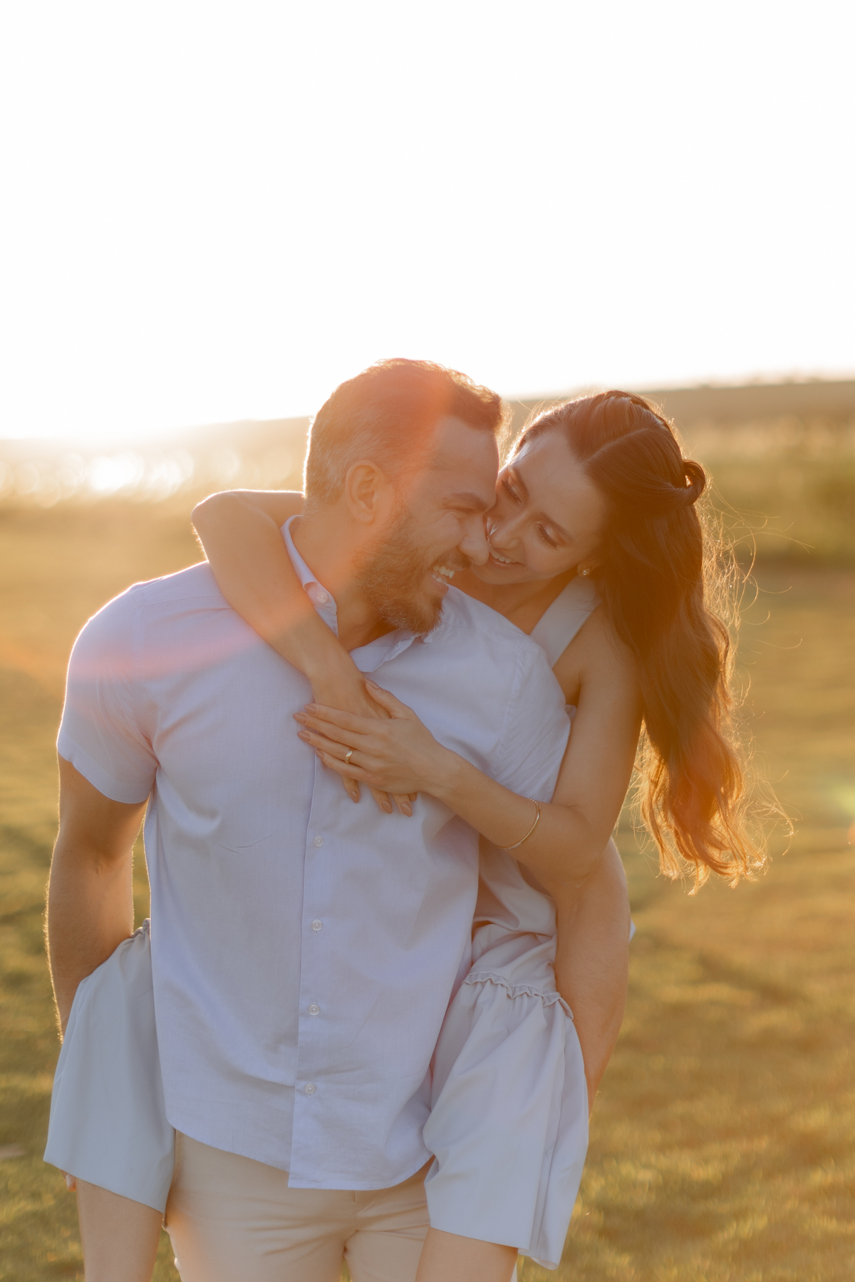 Casal abraçado no campo com por  do sol