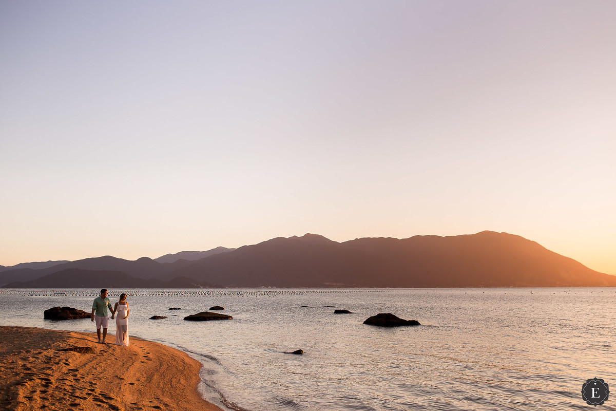 casal andando pela praia em fotos de ensaio de gestante