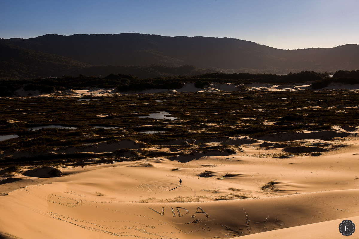 caminhante pela areia das dunas da joaquina em Florianópolis sc