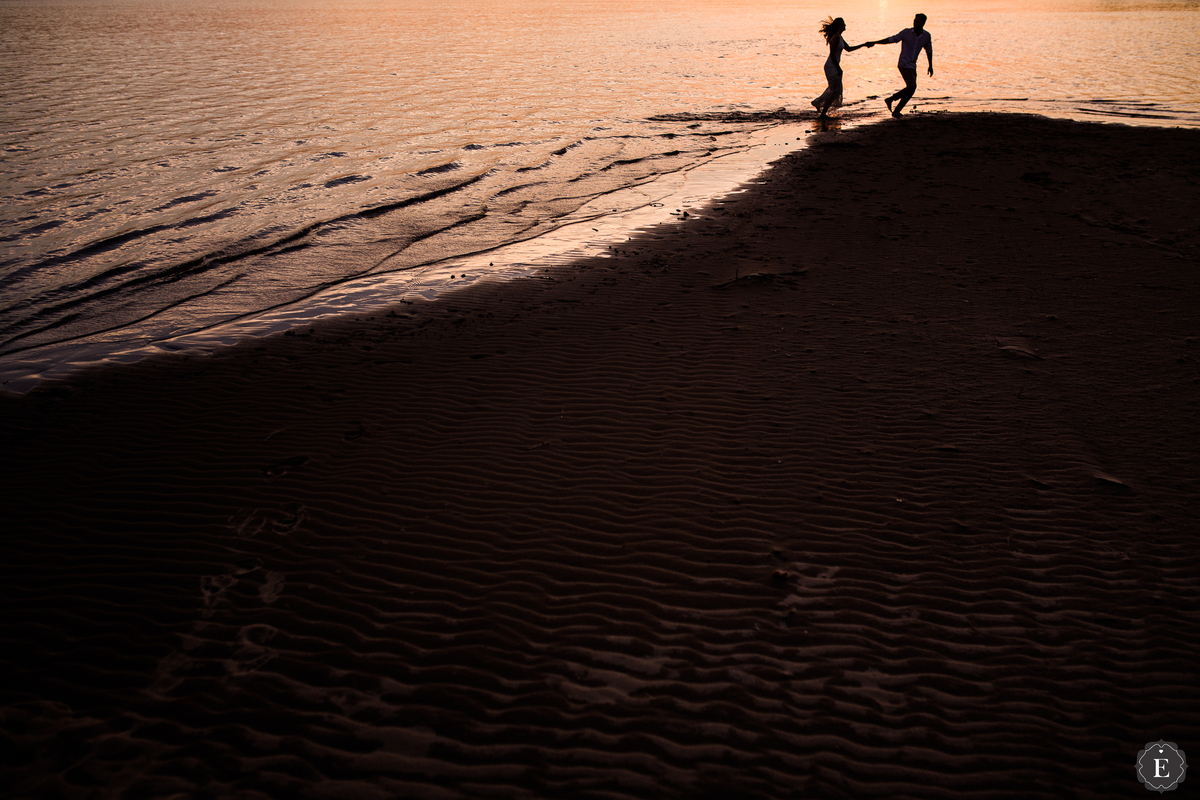 casal apaixonado correndo na praia com um lindo por do sol no rio parana