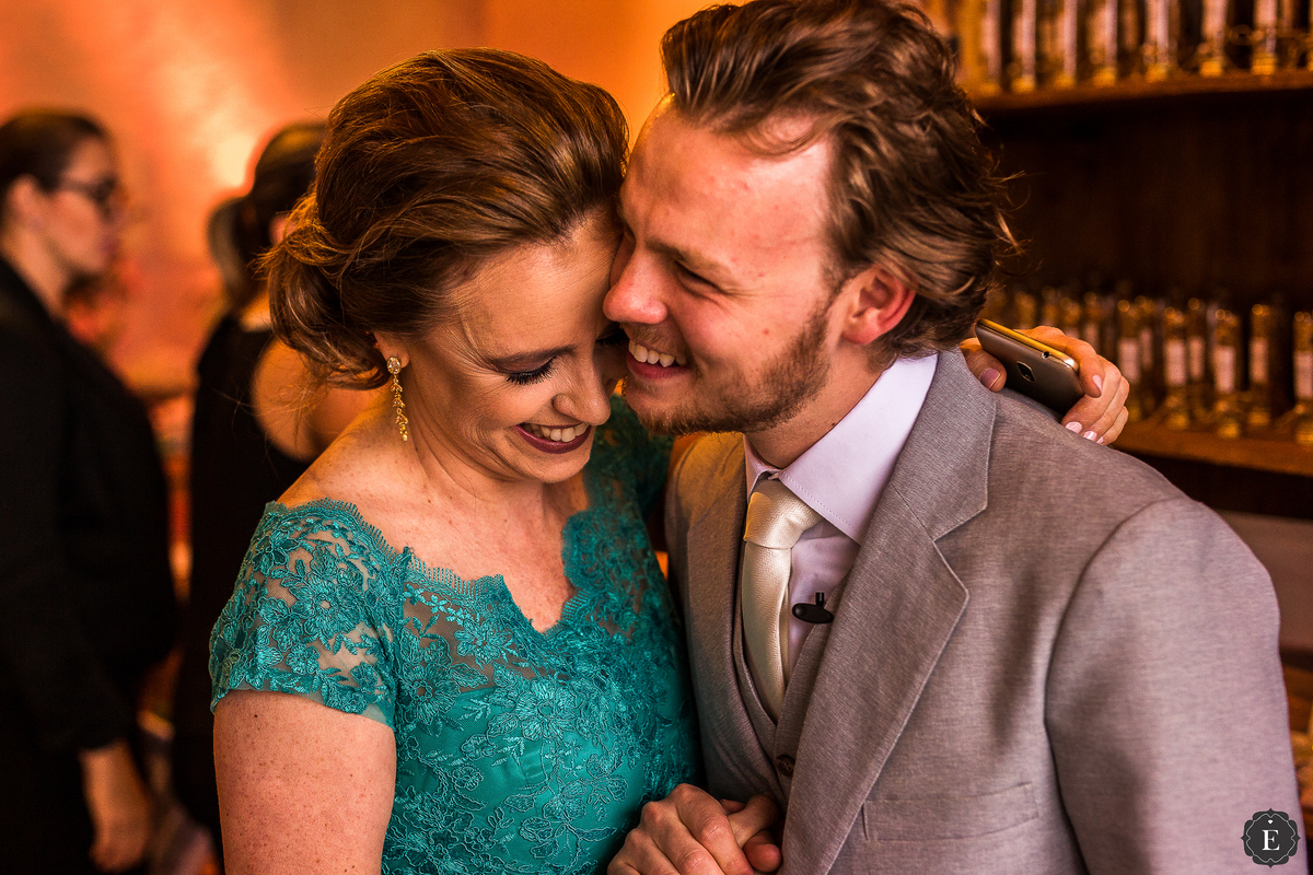 mae emocionada ao abraçar o noivo com terno cinza claro em casamento de dia no parana