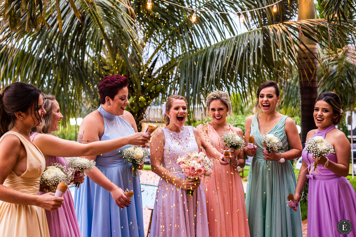 lindas madrinhas de vestido em cores pasteis e delicadas jogando confetes dourados na noiva em casamento no campo em maringa
