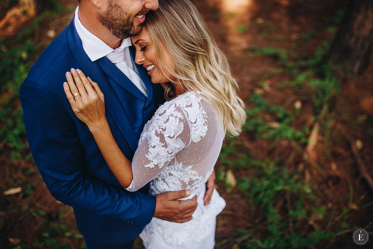 linda noiva apaixonada com seu vestido de noiva de tule vintage e renda delicada com seu noivo de terno azul em fotos pós wedding no parana 