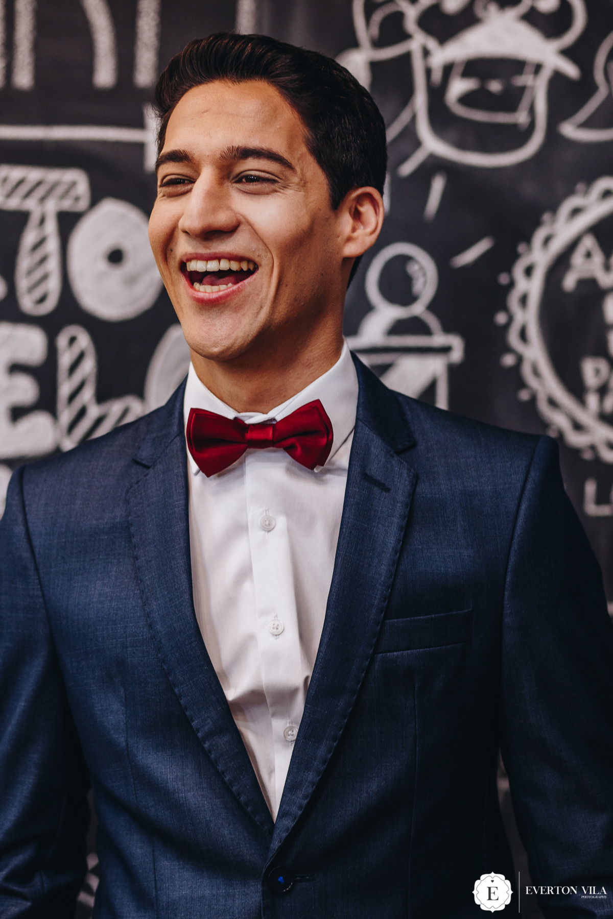 noivo sorrindo com seu terno azul escuro e gravata vermelha para se casar de dia no parana