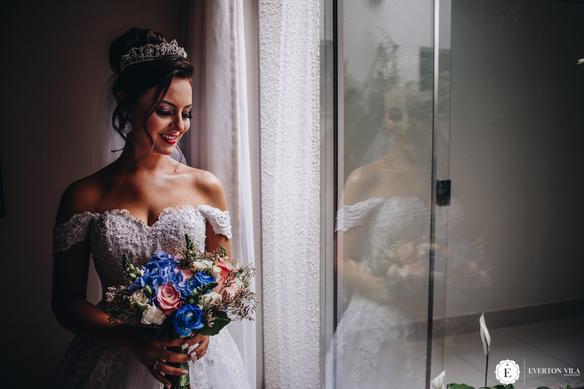 noiva segurando seu buque de noiva colorido com flor azul e penteado despojado para casamento no campo