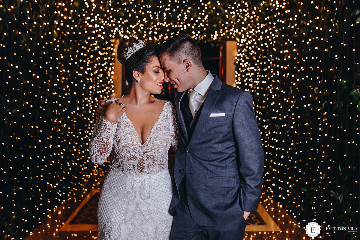 noiva e noivo abraçados sob varal de luzes na decoraçao de seu casamento moderno em cianorte parana