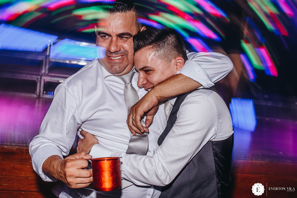 noivo feliz dançando com seu padrinho de casamento na sua festa