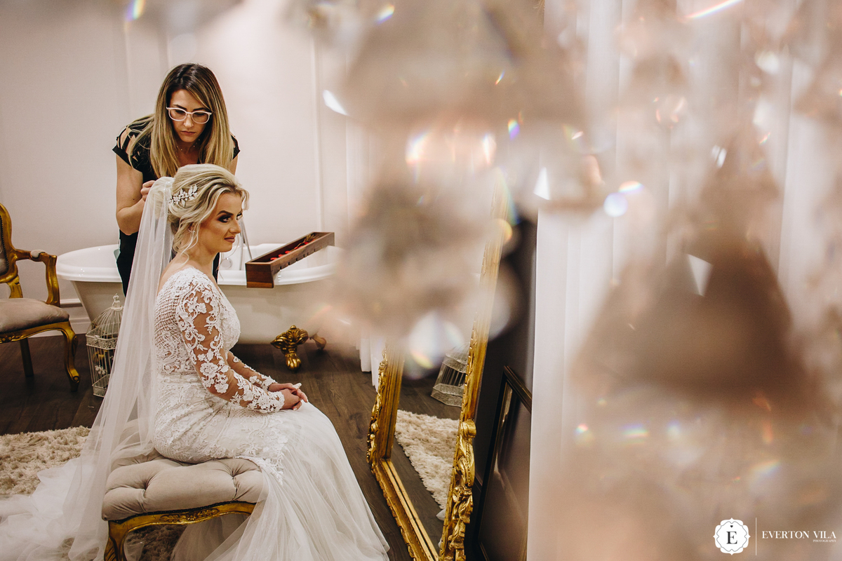 Noiva Aimee com seu vestido de renda de manga longa se arrumando no estudio le pequeno em maringa pr