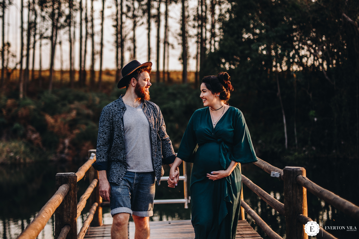 gestante linda com seu marido caminhando de mãos dadas em ponte no Paraná
