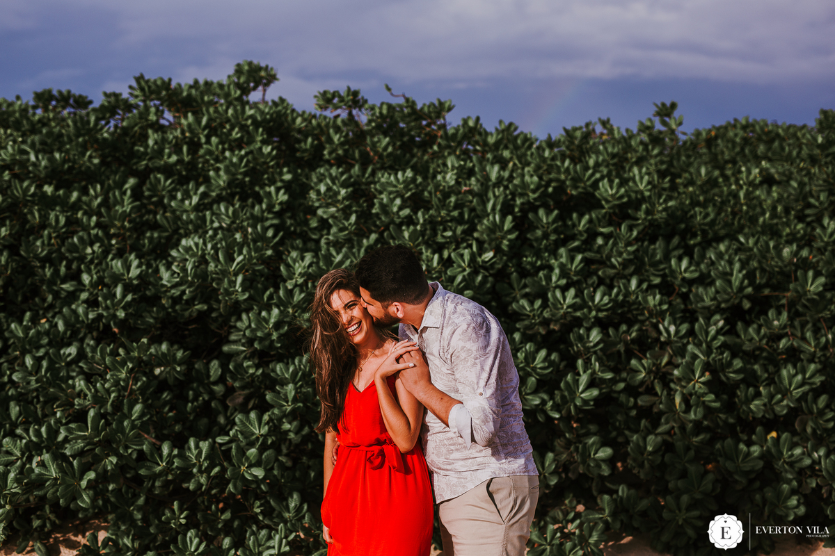 noivo beijando sua noiva com vestido vermelho lindo em parede verde