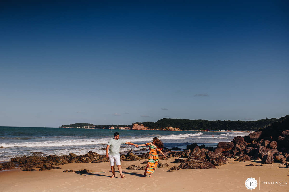 casal correndo pelas pedras da praia da pipa no Nordeste