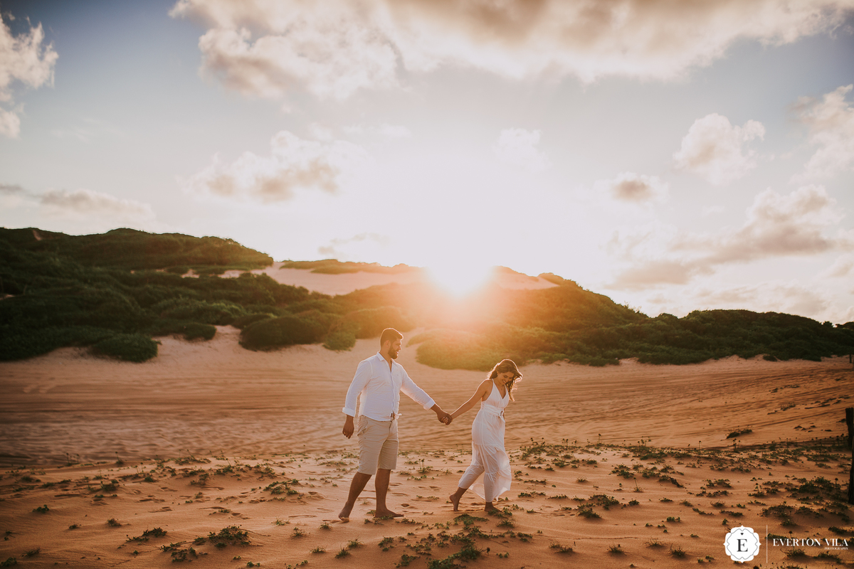 noivos caminhando com roupas claras e leves em ensaio pré casamento na praia de pipa rn