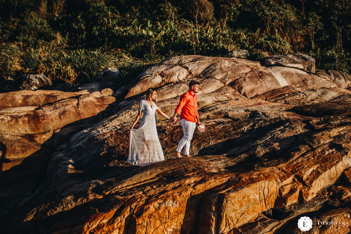 casal caminhando de mãos dadas nas pedras em balneário camboriú