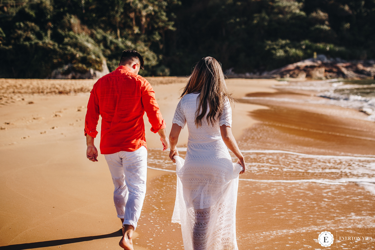 noiva segurando seu lindo vestido em praia do estaleiro 