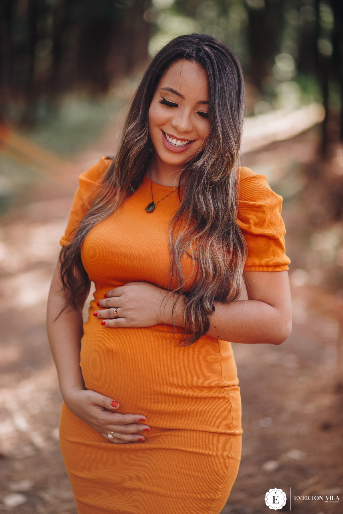 linda gestante com vestido laranja em ensaio de gestante