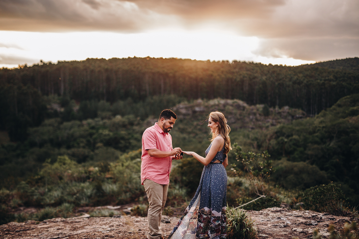 noivo colocando aliança na mão de sua noiva em montanha